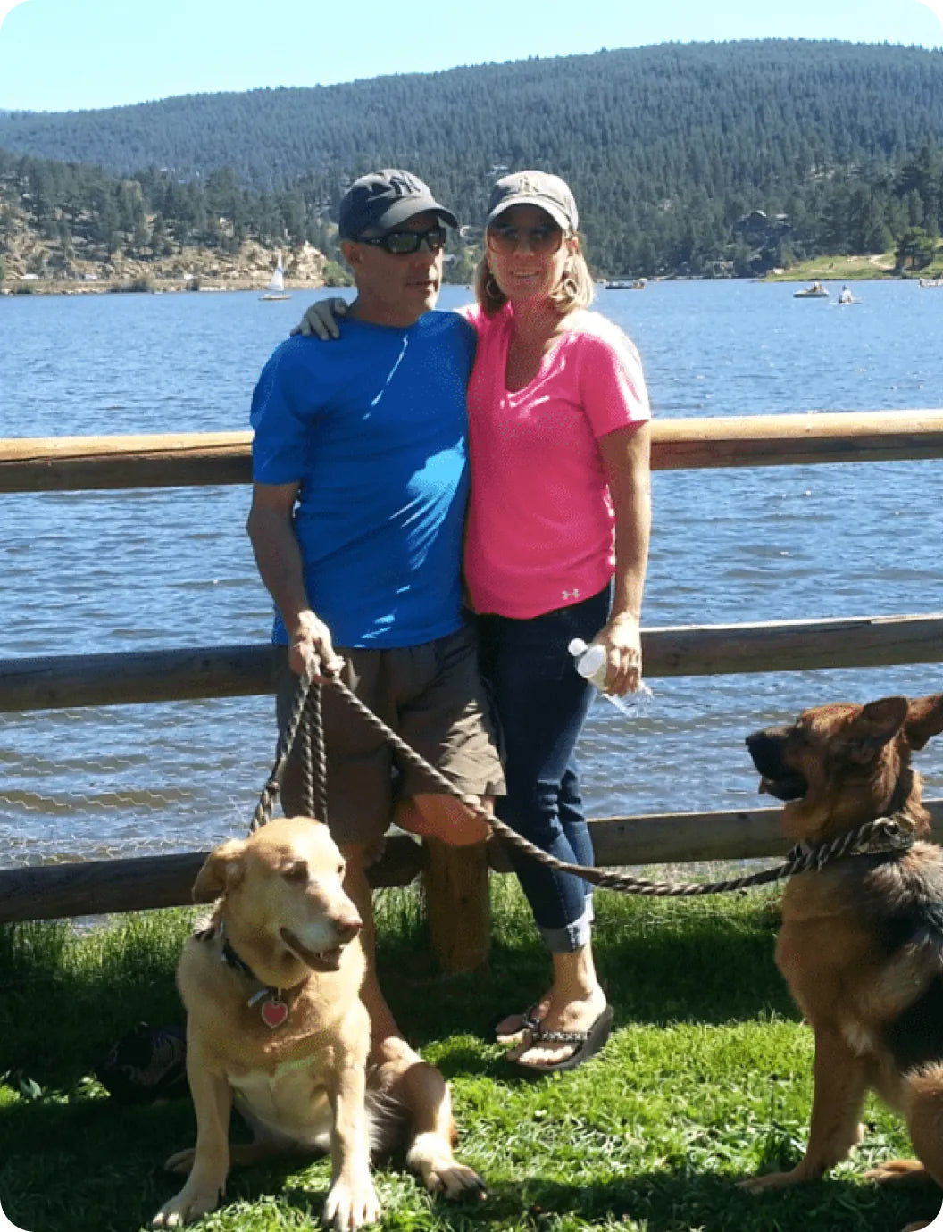A couple walking two dogs on a lakeside trail in Colorado