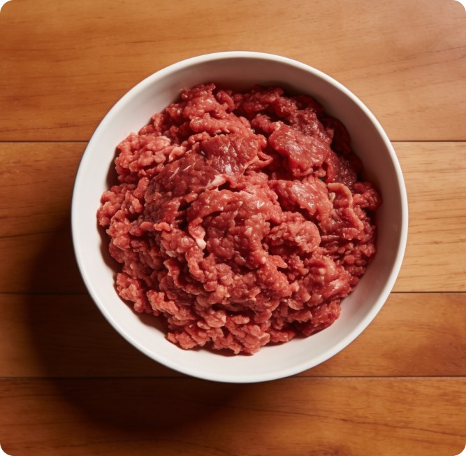 A bowl of raw ground meat on a wooden table