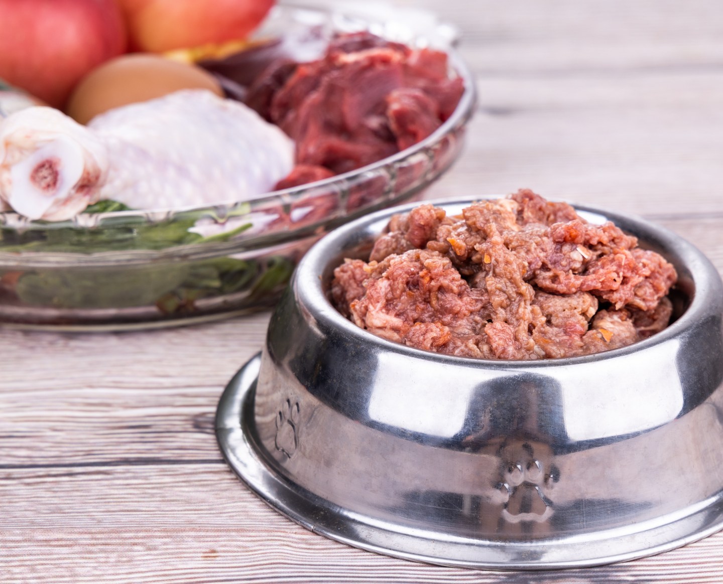 A stainless steel bowl of raw blend beside a dish of raw ingredients